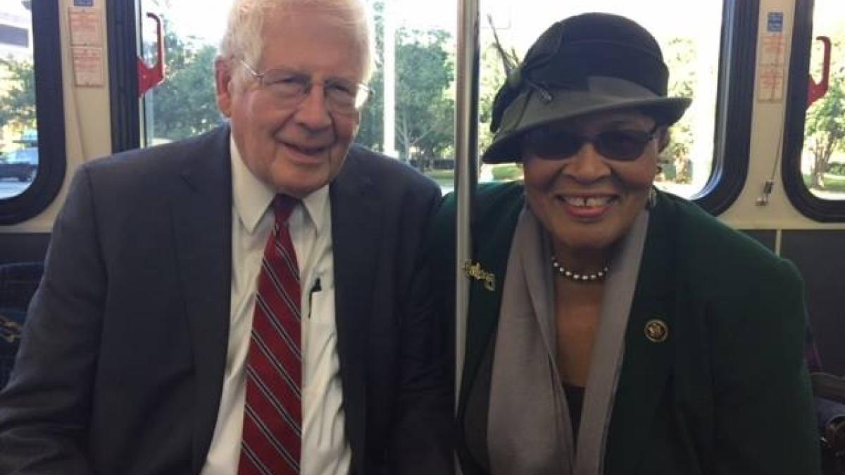 Rep. Alma Adams and Rep. David Price sitting together and smiling on a CATS bus in Charlotte